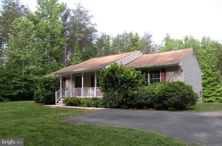 a view of a house with a yard plants and large tree