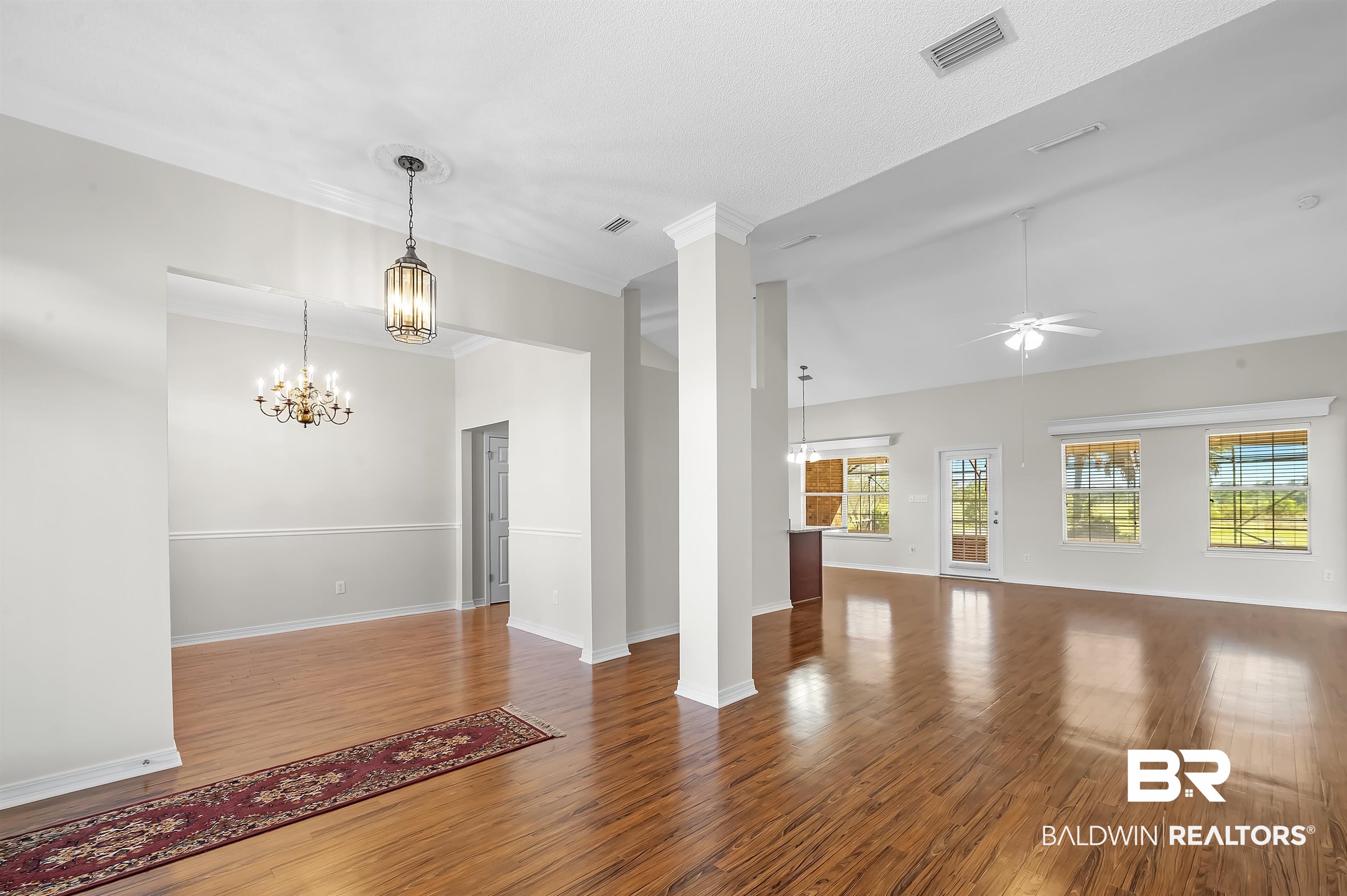 421 Collinwood Loop Foley, AL 36535 - Photo 17 of 62 Unfurnished living room with decorative columns, ceiling fan with notable chandelier, and hardwood / wood-style floors