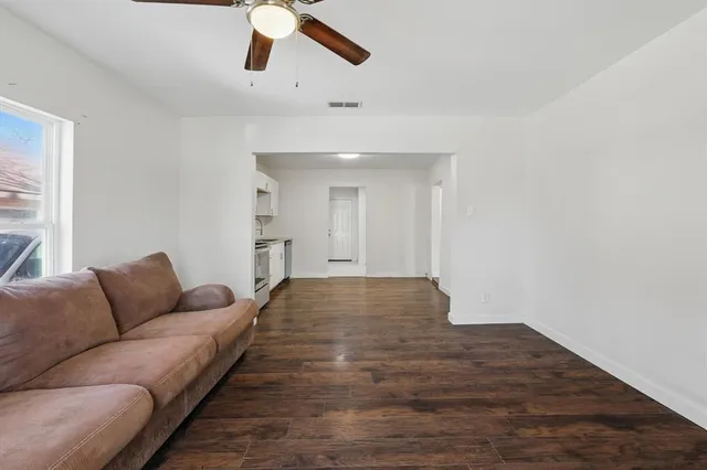 an empty room with wooden floor and a ceiling fan