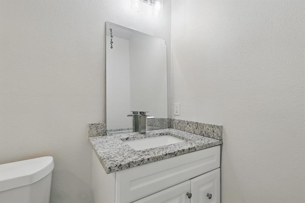 1805 Daniel Street Fort Worth, TX 76104 - Photo 21 of 38 a bathroom with a granite countertop sink and a toilet
