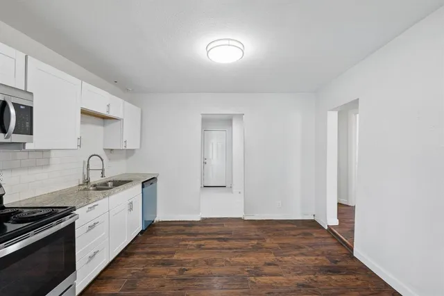 a kitchen with granite countertop a stove sink and microwave