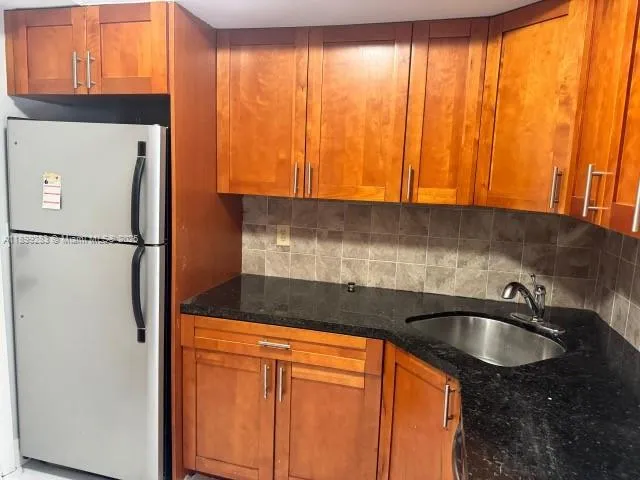 a kitchen with a sink a refrigerator and cabinets