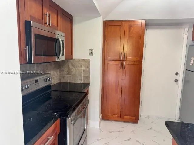 a kitchen with granite countertop stainless steel appliances a stove and a microwave