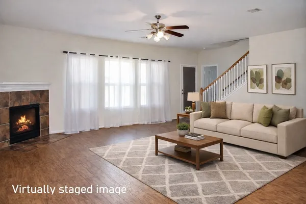 a view of an empty room with chandelier fan and wooden floor