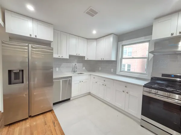 a kitchen with granite countertop white cabinets and stainless steel appliances