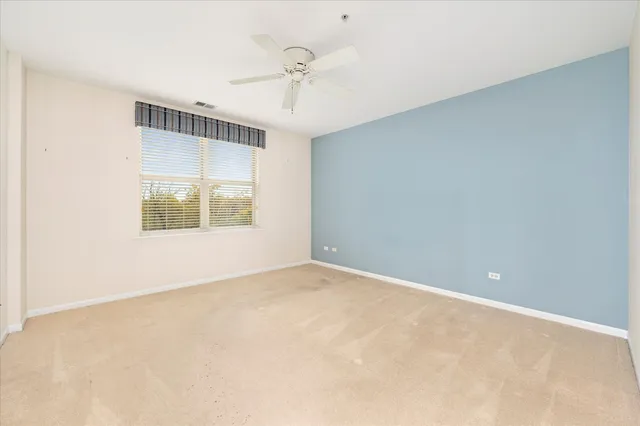 an empty room with a window and a ceiling fan