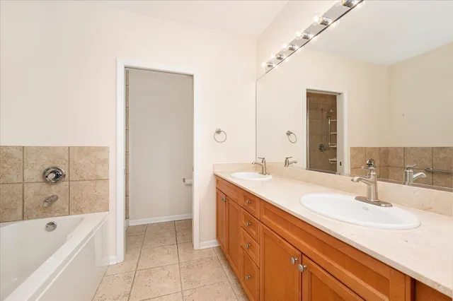 a bathroom with a double vanity sink mirror and bathtub