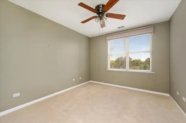 an empty room with ceiling fan and window