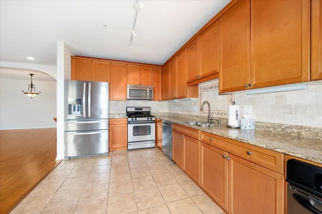 a kitchen with stainless steel appliances granite countertop a refrigerator a sink dishwasher a stove with wooden cabinets