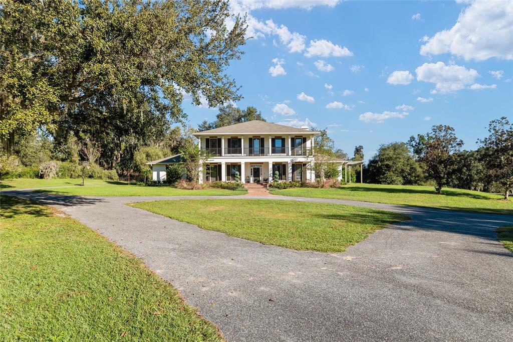 a view of a house with a big yard and large trees