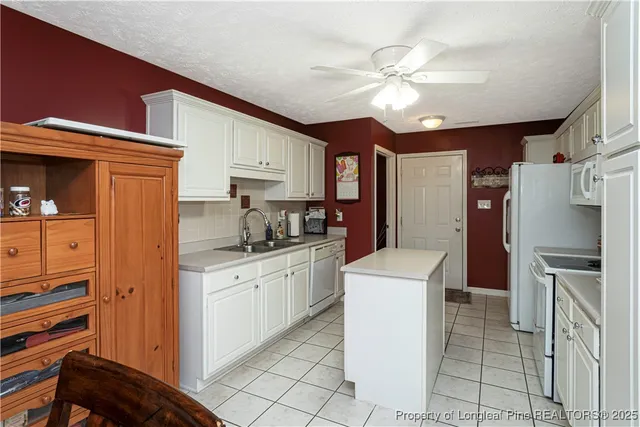 a kitchen with granite countertop a sink stainless steel appliances and white cabinets