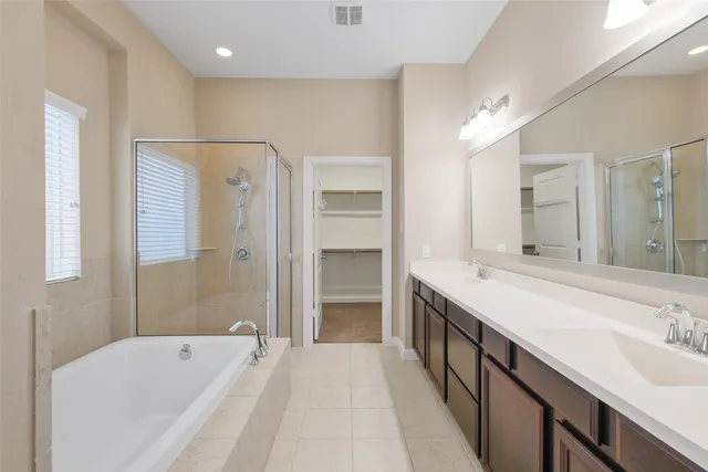 a spacious bathroom with a tub sink shower and mirror