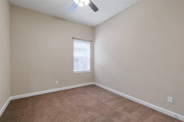 an empty room with a chandelier fan and windows
