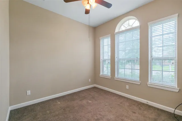 an empty room with window chandelier fan and windows