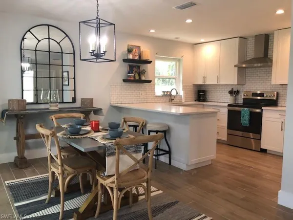 a kitchen with stainless steel appliances kitchen island granite countertop a sink a stove a dining table and chairs