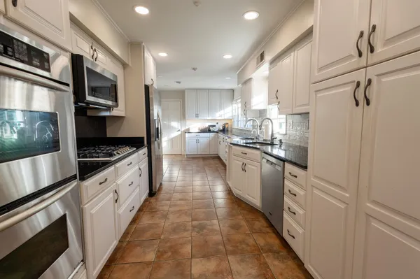 a large kitchen with stainless steel appliances kitchen island granite countertop a large counter top space a stove a microwave and a refrigerator