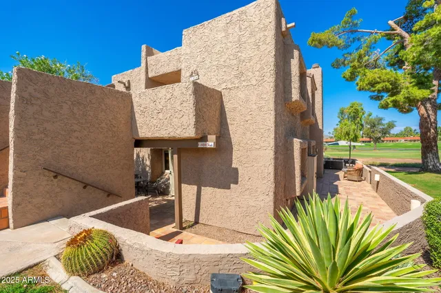a backyard of a house with table and chairs and a large tree