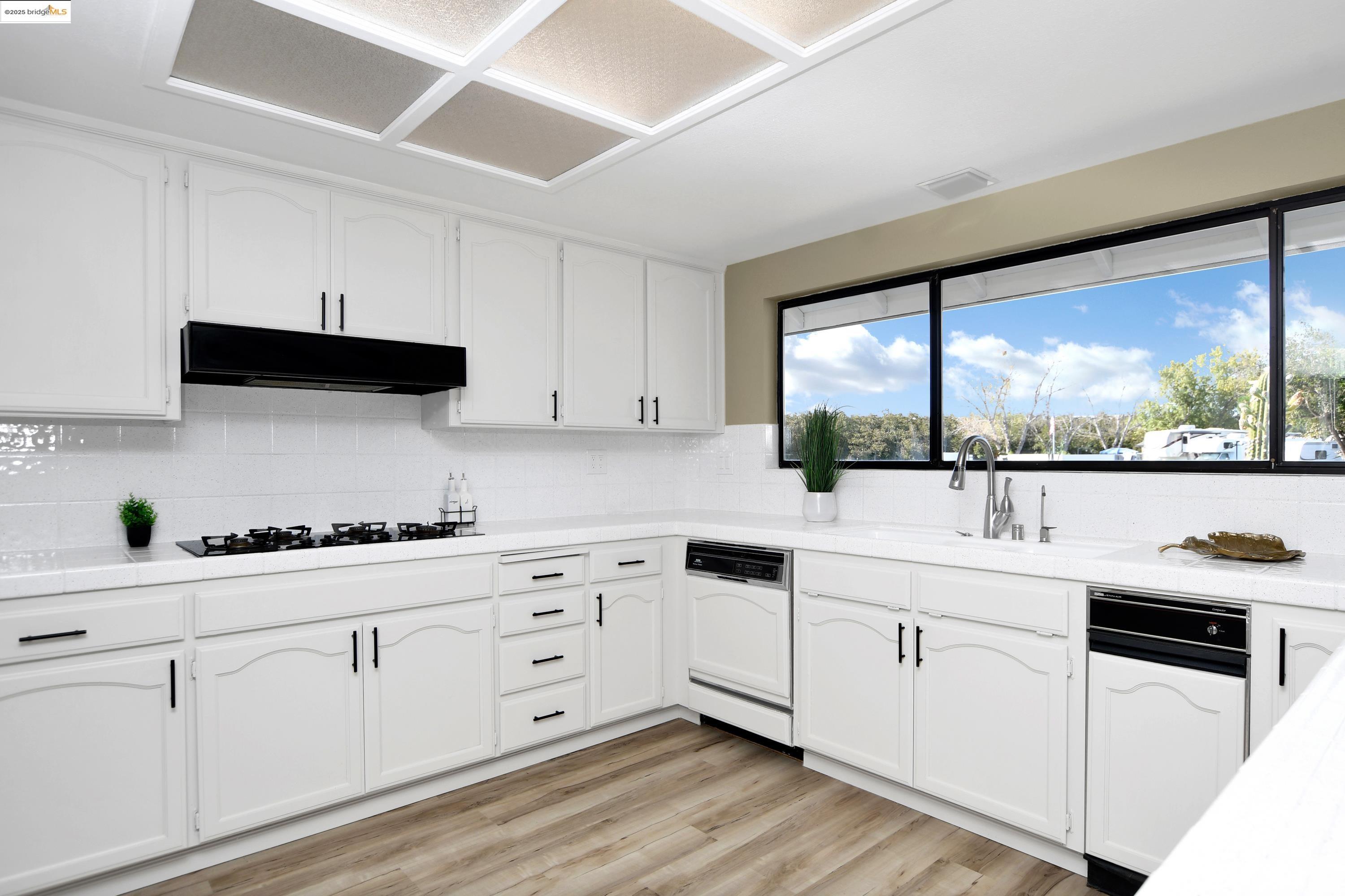 23701 Marsh Creek Road Brentwood, CA 94513 - Photo 9 of 52 a kitchen with white cabinets a sink a stove and a microwave