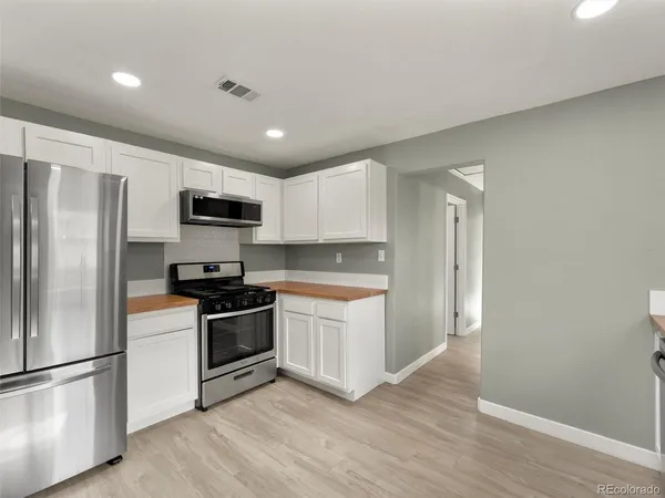 a kitchen with a refrigerator stove and wooden floor