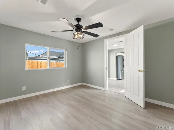 an empty room with wooden floor fan and windows