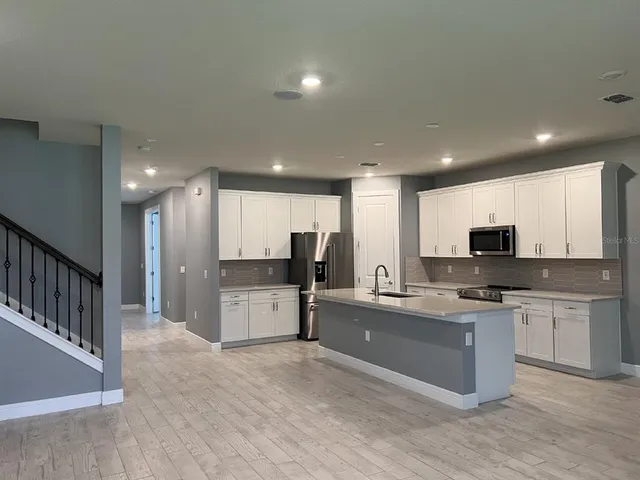 a large kitchen with stainless steel appliances kitchen island granite countertop a sink and cabinets