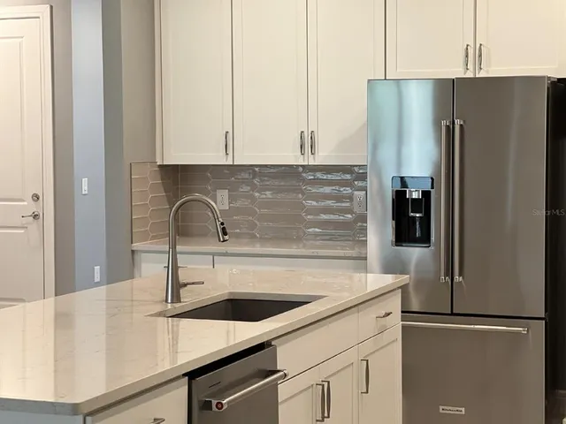 a kitchen with stainless steel appliances granite countertop a refrigerator and a sink