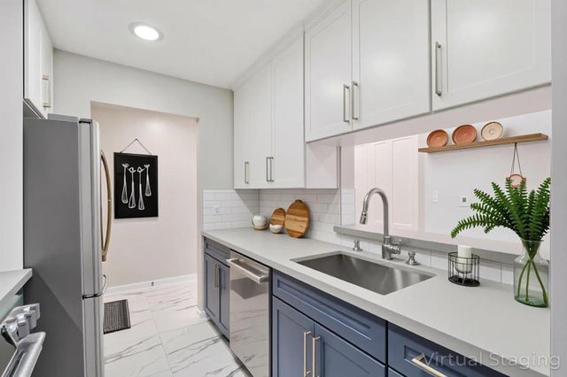 a kitchen with stainless steel appliances a sink dishwasher a refrigerator and white cabinets with wooden floor