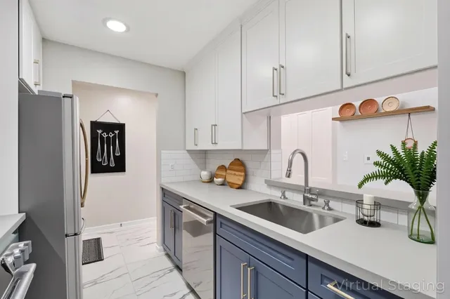 a kitchen with stainless steel appliances a sink dishwasher a refrigerator and white cabinets with wooden floor