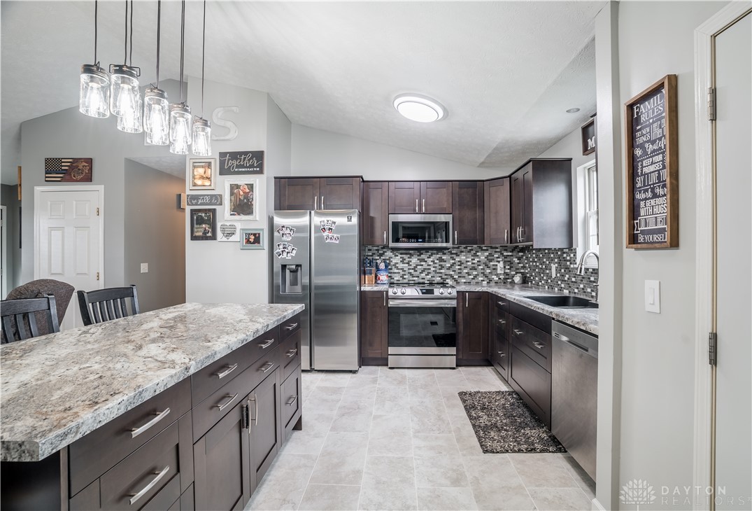 1442 Langdon Road Sidney, OH 45365 - Photo 9 of 34 This modern kitchen features rich cabinetry, stainless steel appliances, and a spacious island, perfect for culinary endeavors.
