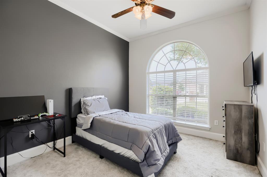 603 Ash Street Pilot Point, TX 76258 - Photo 18 of 28 Bedroom featuring a large arched window with horizontal blinds, carpeted flooring, and crown molding