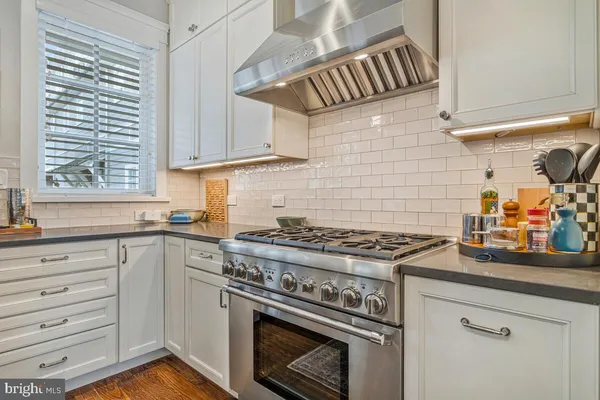 a kitchen with stainless steel appliances kitchen island granite countertop a table chairs in it and a window