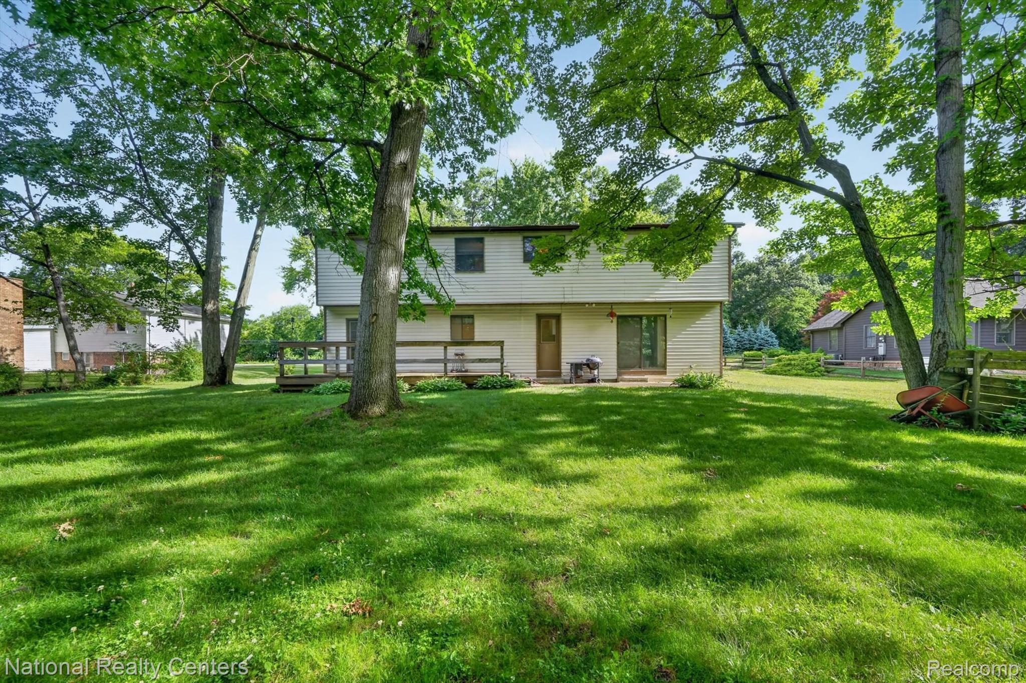 3107 Dean Road Lambertville, MI 48144 - Photo 44 of 45 Expansive rear yard featuring mature trees, a wooden deck, and a sliding glass door