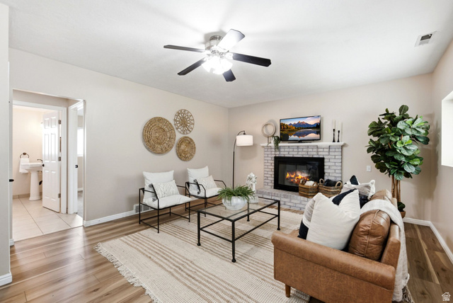 11875 South Elm Ridge Road Sandy, UT 84094 - Photo 22 of 53 Living area featuring wood-finish flooring, a white brick fireplace, and a ceiling fan
