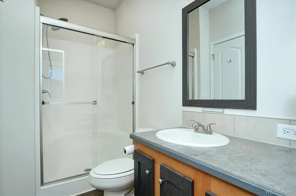 a bathroom with a granite countertop sink toilet and shower