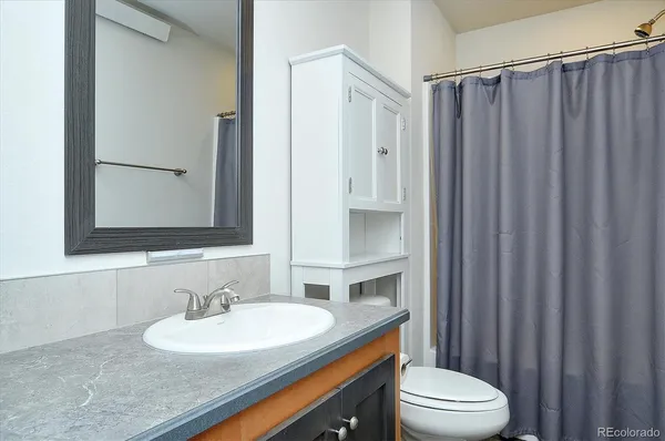 a bathroom with a granite countertop sink vanity mirror and toilet