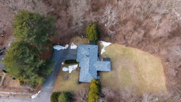 an aerial view of a house with a yard and large trees