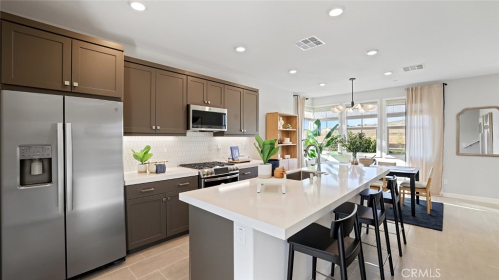 a kitchen with a refrigerator a stove a sink a dining table and chairs