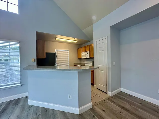a living room with stainless steel appliances a wooden floor a rug and a window