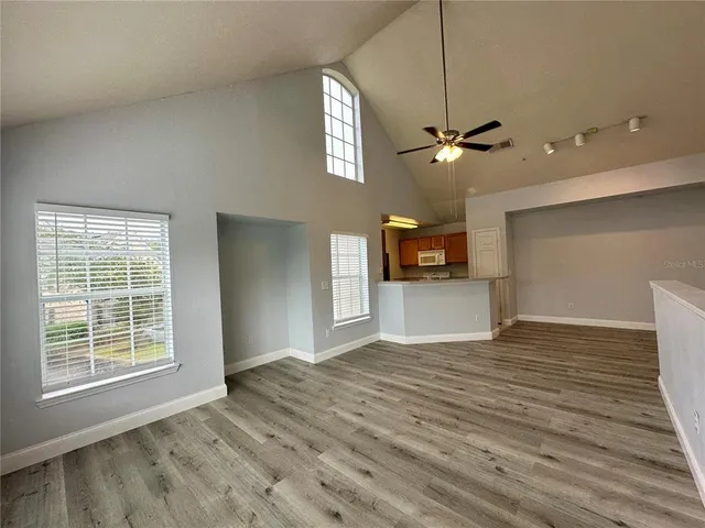a view of an empty room with a window and wooden floor