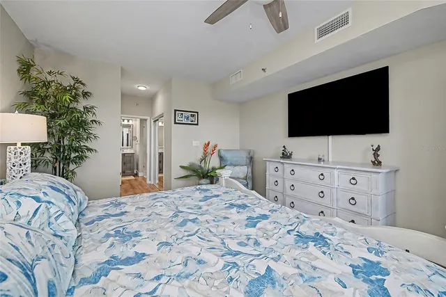 a bedroom with a bed a flat tv screen and dresser