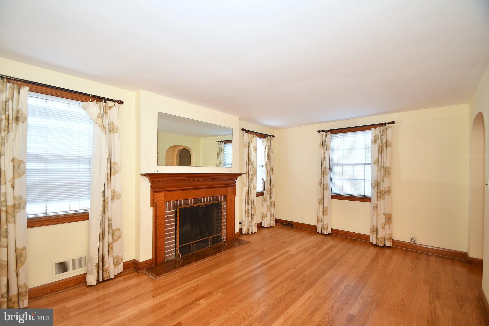 7009 Mornington Road Dundalk, MD 21222 - Photo 6 of 48 an empty room with wooden floor fireplace and windows