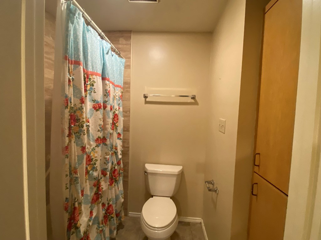802 Lois Street Kerrville, TX 78028 - Photo 12 of 25 a white toilet sitting next to a shower curtain