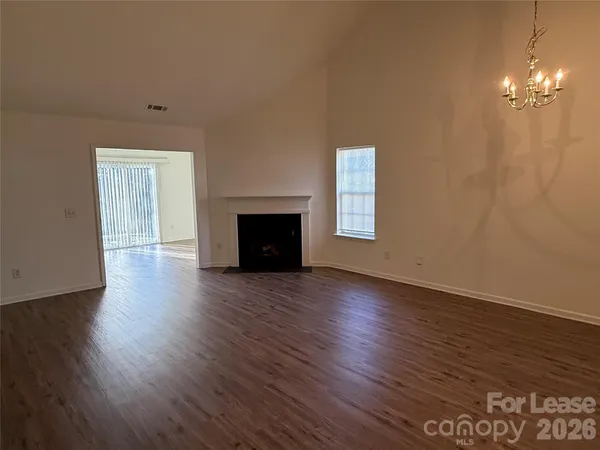 an empty room with wooden floor fireplace and windows