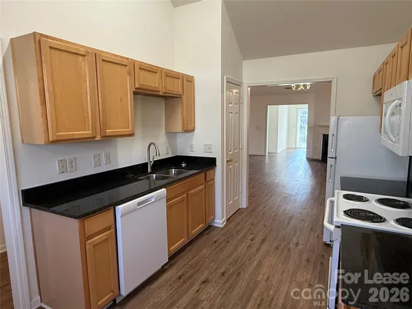 a kitchen with granite countertop a sink a stove and wooden floor