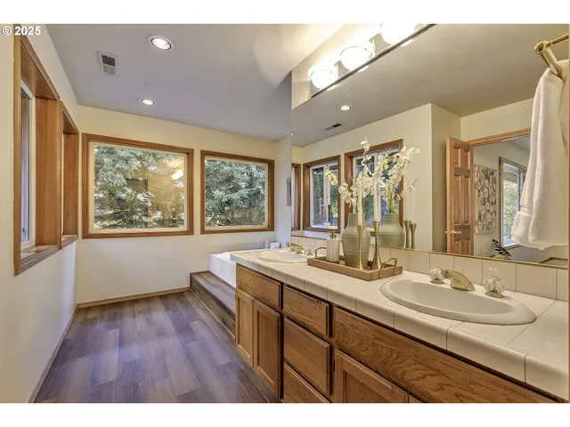 a bathroom with a double vanity sink a large mirror and a large window