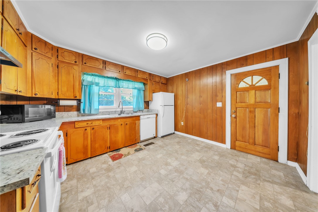 107 Burton Road Anderson, SC 29625 - Photo 14 of 33 Rich wood paneling and matching cabinetry define this cozy kitchen space with stone countertops.