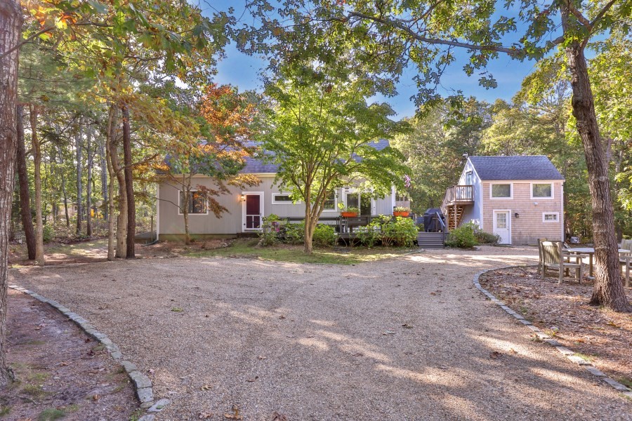a front view of a house with a dirt yard and a large tree