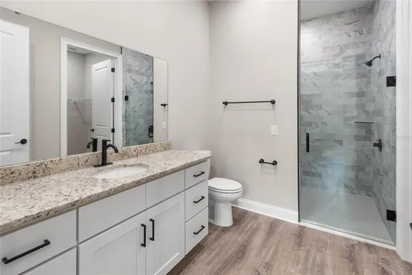 a bathroom with a granite countertop sink a toilet and shower