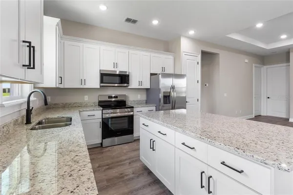 a kitchen with granite countertop a sink stainless steel appliances and white cabinets