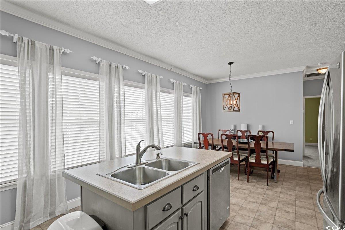 706 Beverly Hills Road Camden, SC 29020 - Photo 5 of 25 Kitchen with a center island with sink, appliances with stainless steel finishes, light countertops, crown molding, and a textured ceiling